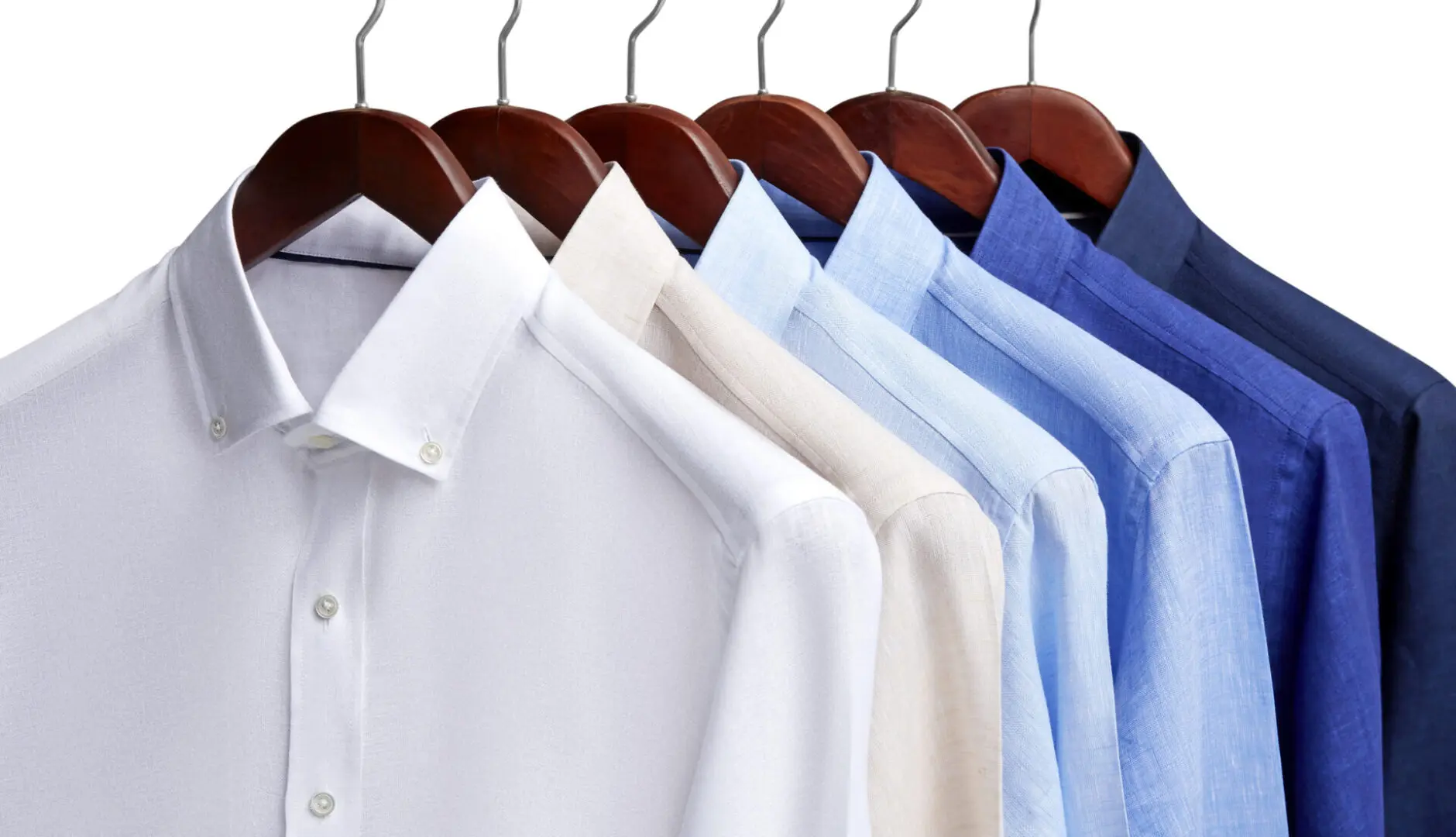 Assorted dress shirts on wooden hangers.